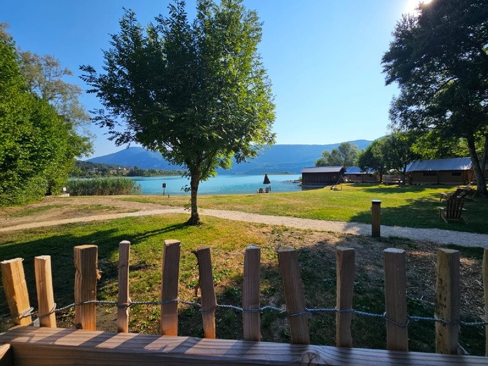 La vue sur la plage du Domaine du Lac tôt le matin depuis la terrasse d'une tente Bois & Toile - Photo CE La vue sur la plage du Domaine du Lac tôt le matin depuis la terrasse d'une tente Bois & Toile - Photo CE